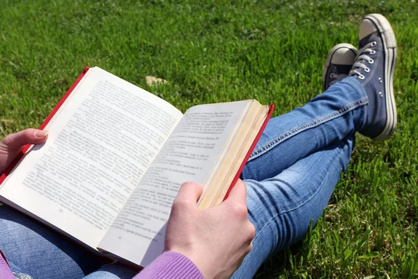 Giovane donna con libro seduta su erba verde — Foto Stock