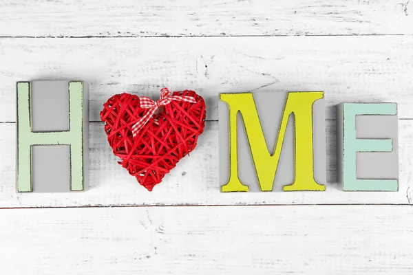 Lettere decorative che formano parola HOME con cuore decorativo su sfondo di legno — Foto Stock