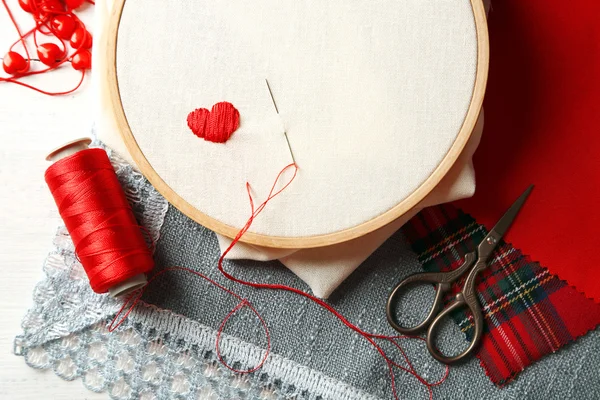 El aro de bordado con tela e hilos de coser rojos en la mesa de cerca — Foto de Stock