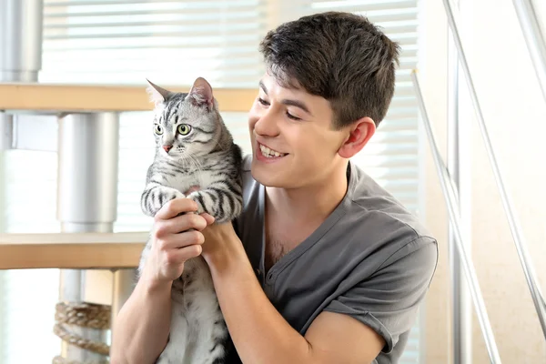 Knappe jongeman met leuke kat zit op stappen thuis — Stockfoto