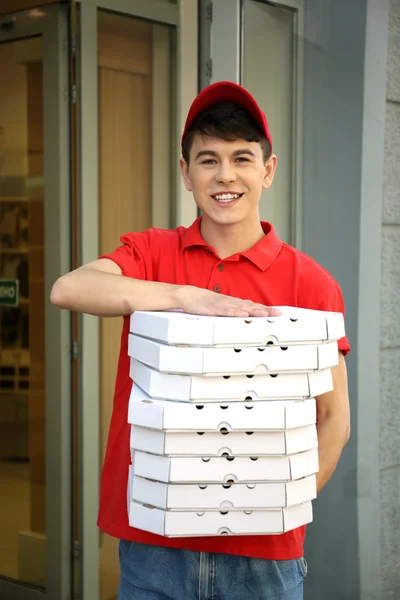 Jovem entregando caixa de pizza perto de casa — Fotografia de Stock