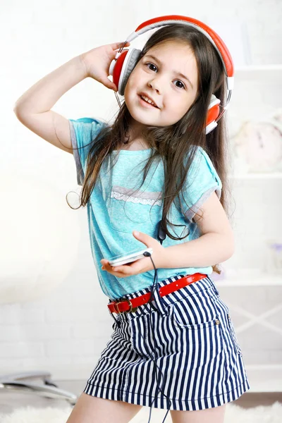 Beautiful little girl listening to music in room — Stock Photo, Image