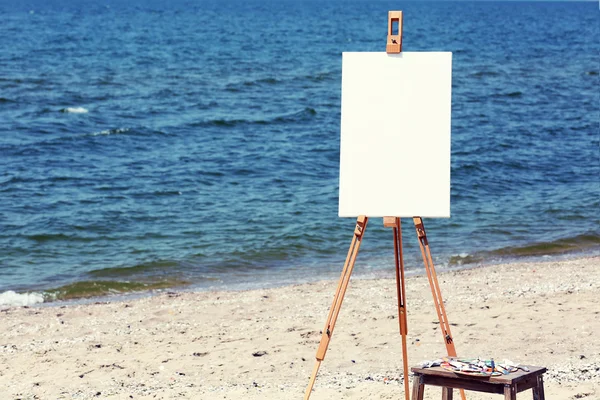 Easel with canvas on beach — Stock Photo, Image