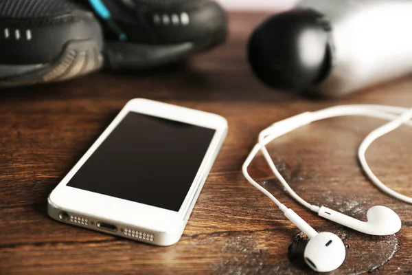 Zapatillas y auriculares en mesa de madera, primer plano — Foto de Stock