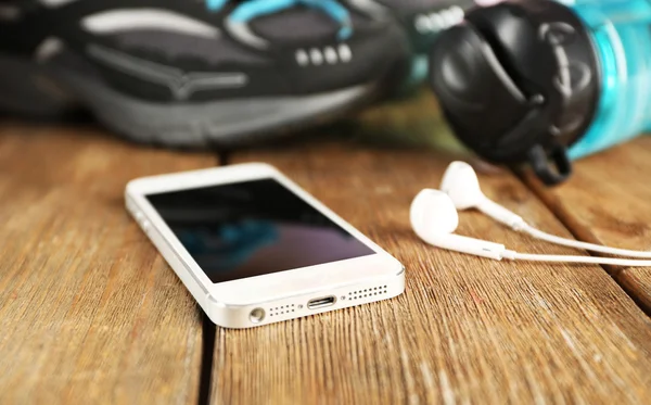 Zapatillas y auriculares en mesa de madera, primer plano — Foto de Stock