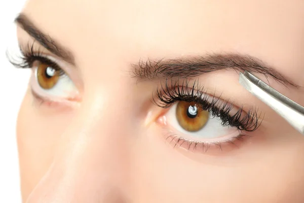 Young woman plucking eyebrows with tweezers close up — Stock Photo, Image