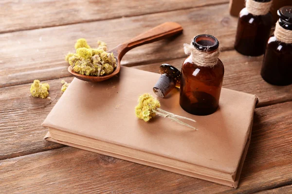 Old book with dry flowers and bottles on table close up — Stock Photo, Image