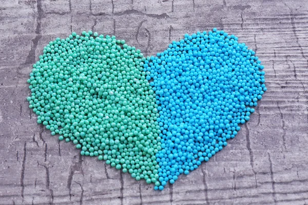 Färgglada pärlor i hjärta form på trä bakgrund — Stockfoto