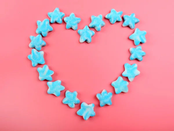 Blue candies heart shaped on pink background — Stock Photo, Image