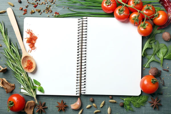 Livro de receitas aberto com ervas frescas, tomates e especiarias em fundo de madeira — Fotografia de Stock