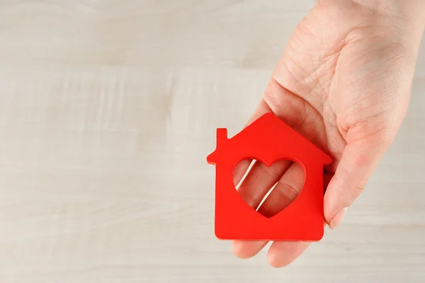 Weibliche Hand mit Modell des Hauses auf Holztischhintergrund — Stockfoto