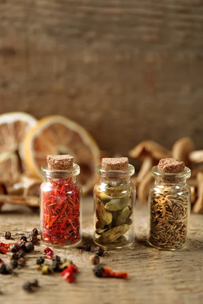 Assortiment van specerijen in glazen flessen op houten achtergrond — Stockfoto
