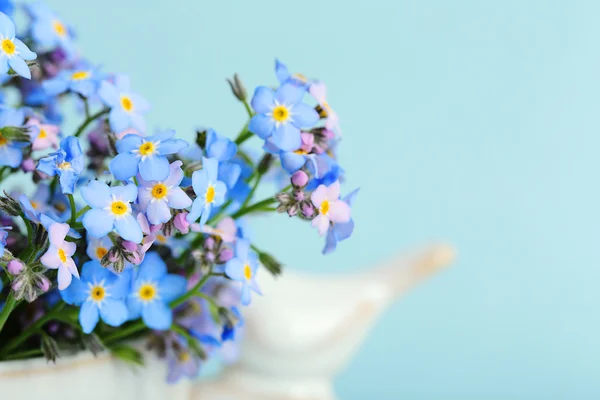 Forget-me-nots bloemen in cup, op blauwe achtergrond — Stockfoto