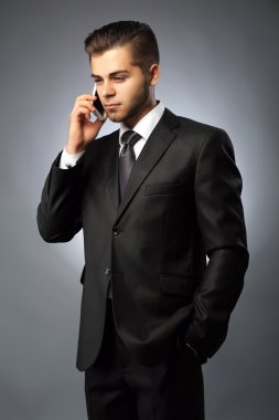 yakışıklı işadamı telefon gri arka plan üzerinde konuşurken