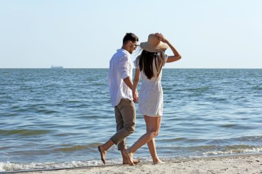 Genç bir çift sahilde yürüyor.