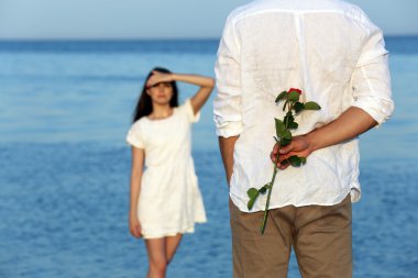 Çiçek kız arkadaşı için sahilde veren genç adam