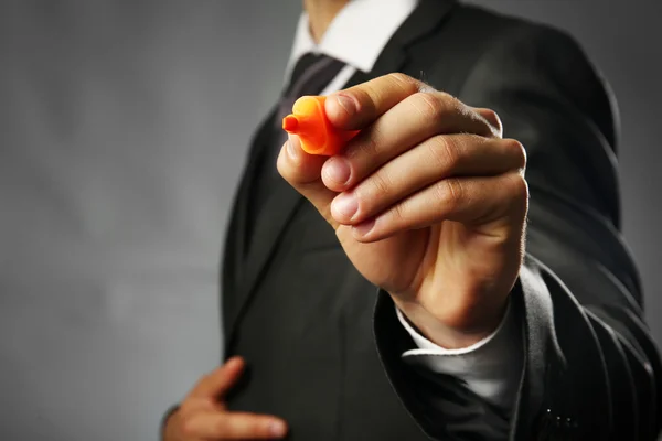 Businessman holding marker on gray background — Stock Photo, Image