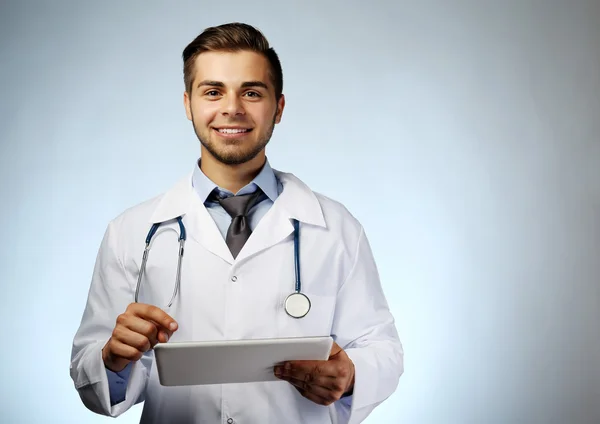 Mannelijke arts met tablet op blauwe achtergrond — Stockfoto