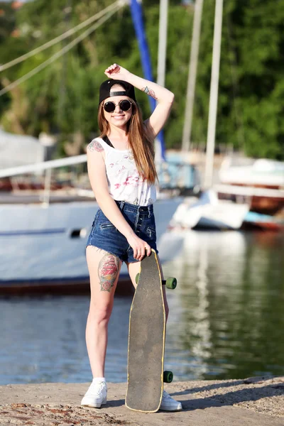 Mooie getatoeëerd meisje met skateboard, buitenshuis — Stockfoto