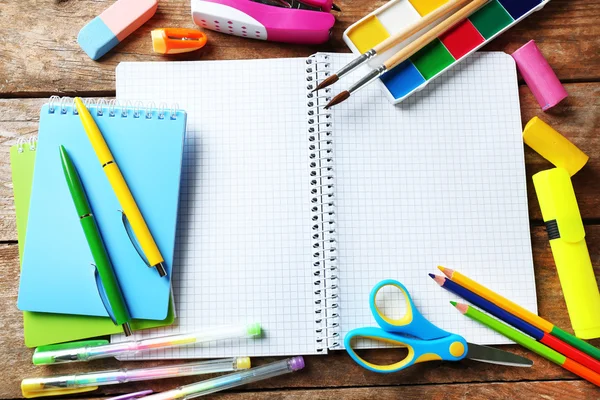 Notebook en heldere school briefpapier op oude houten tafel — Stockfoto