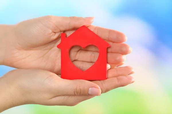 Female hands holding model of house on bright background — Stock Photo, Image