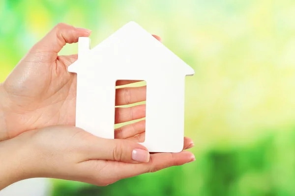 Female hands holding model of house on bright background — Stock Photo, Image