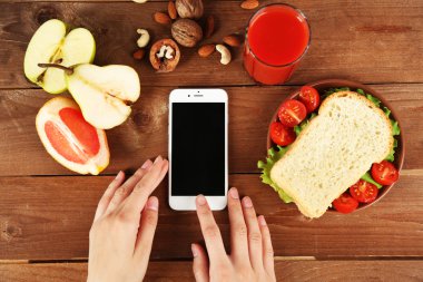 Gıda ve ahşap arka plan üzerinde eller içinde hareket eden telefon