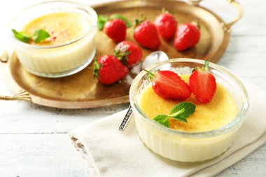 Creme brulee tatlı taze çilek ve renk ahşap zemin üzerine nane yaprakları ile
