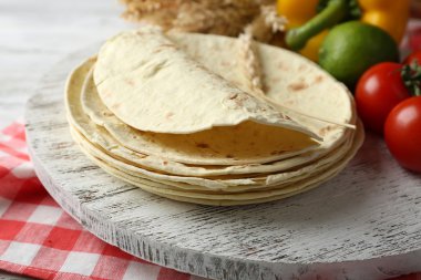 Ev yapımı kepekli un tortilla ve ahşap masa arka plan üzerinde kesme tahtası üzerinde sebze yığını