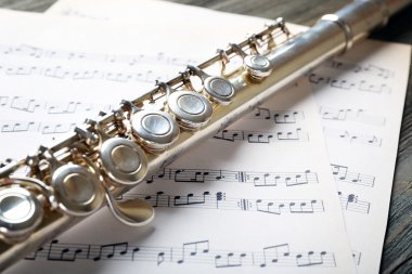 Ahşap masa üzerine müzik notlar ile gümüş flüt yakın çekim