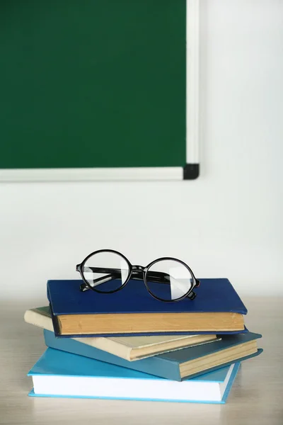 Bücherhaufen und Gläser auf dem Tisch im Unterricht — Stockfoto