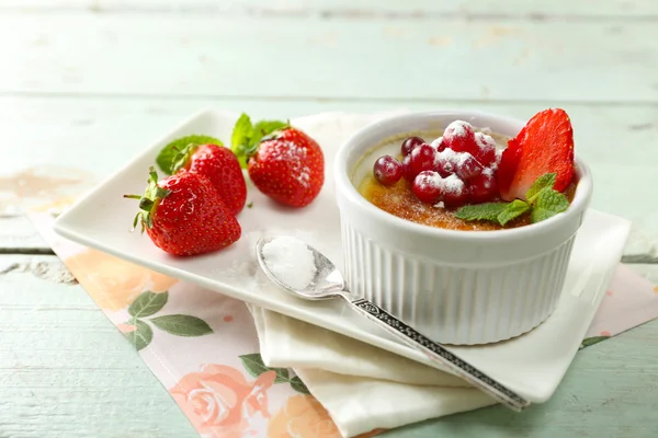 Postre de crema brulee con fresas frescas y hojas de menta, sobre fondo de madera de color — Foto de Stock