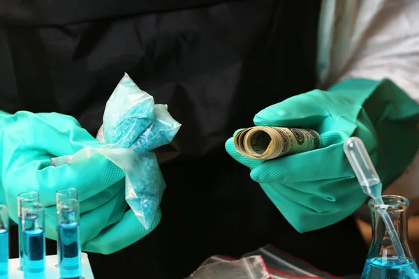 Químicos sosteniendo bolsa de plástico con metanfetamina azul y dinero en laboratorio —  Fotos de Stock