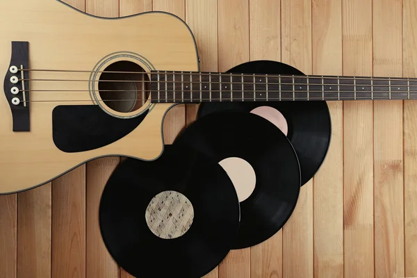 Guitar and vinyl records on wooden table close up — Stock Photo, Image