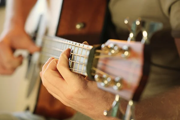 Молодой человек играет на акустической гитаре вблизи — стоковое фото