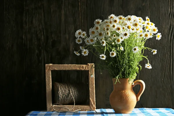 Beautiful bouquet of daisies in pitcher with twine on wooden background — Stock Photo, Image