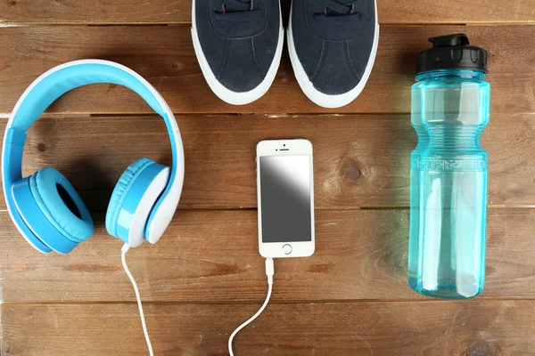 Chaussures de sport avec bouteille d'eau et écouteurs sur fond en bois — Photo