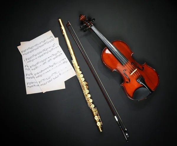 Violino e flauta com notas de música no fundo escuro — Fotografia de Stock