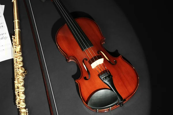 Violon et flûte avec notes de musique sur fond sombre — Photo