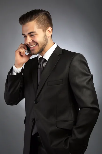 Hombre de negocios guapo hablando por teléfono sobre fondo gris —  Fotos de Stock