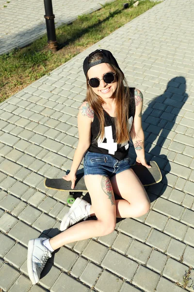 Beautiful tattooed girl with skateboard, outdoors — Stock Photo, Image