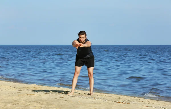 Joven deportista haciendo ejercicio en la playa — Foto de Stock