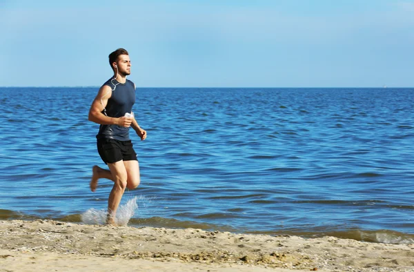 Ung man joggar på stranden — Stockfoto