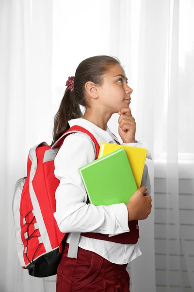 Schönes kleines Mädchen in Schuluniform mit Rucksack und Büchern — Stockfoto