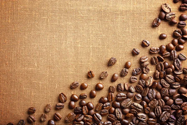 Frame of coffee beans on color sackcloth background — Stock Photo, Image