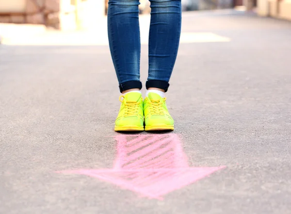 Picioare feminine și săgeată de desen pe fundal trotuar — Fotografie, imagine de stoc