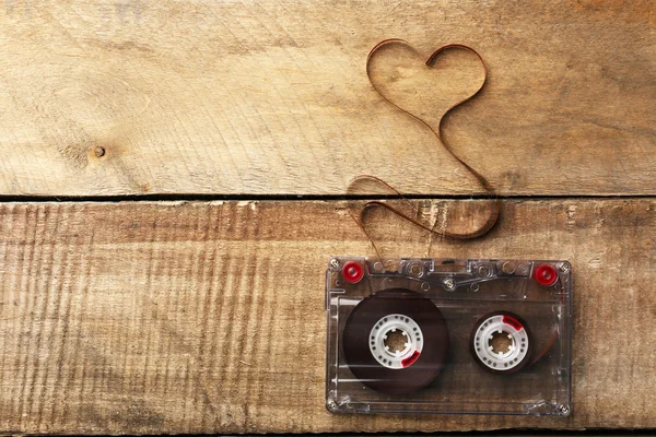 Audiokassette mit Magnetband in Herzform auf Holzgrund — Stockfoto