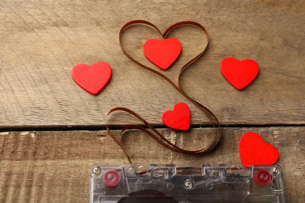 Audio cassette with magnetic tape in shape of heart on wooden background — Stock Photo, Image
