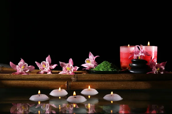 Krásné lázeňské složení s květinami a svíčkami na černém pozadí — Stock fotografie
