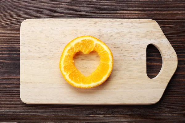 Orange slice with cut in shape of heart on wooden background — Stock Photo, Image